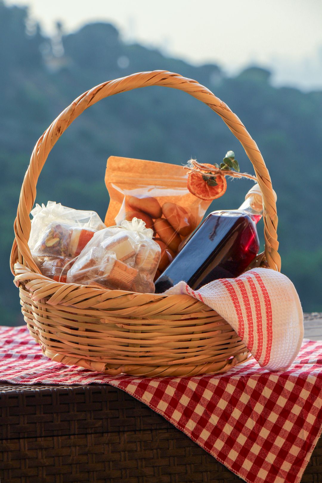 The 3asrouniyeh basket: a bottle of sharab el tout, orange cookies and bags of sweets, on a gingham cloth